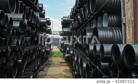 Warehouse of finished plastic pipes industrial outdoors storage site. Manufacture of plastic water Warehouse of finished plastic pipes industrial outdoors storage site. Manufacture of plastic water 42987213