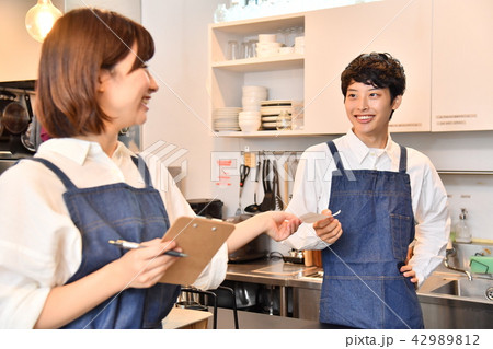 カフェ 男性店員にオーダー伝票を渡す女性店員 カフェ 男性店員にオーダー伝票を渡す女性店員 42989812