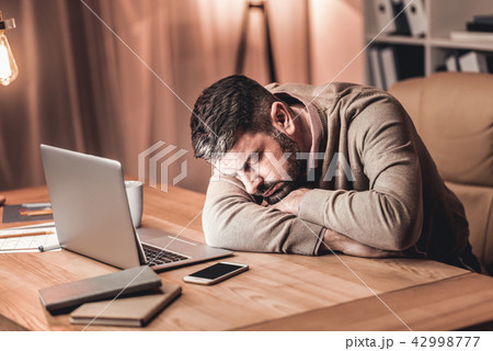 Tired businessman laying on the desk in front of the laptop 42998777