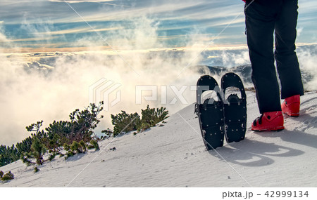 Tall sportsman in warm clothes in snowshoes Tall sportsman in warm clothes in snowshoes 42999134