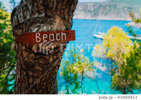 Assos village, Kefalonia. Greece. Beach wooden arrow sign on a pine tree showing direction to small Assos village, Kefalonia. Greece. Beach wooden arrow sign on a pine tree showing direction to small 43000911