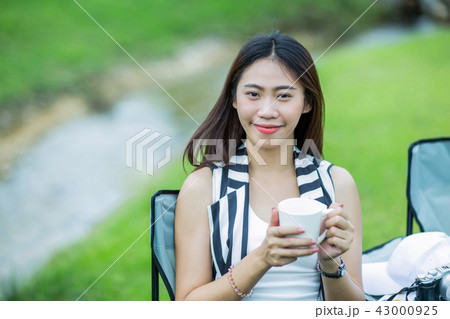 Asian girl holding a cup of coffee near the stream 43000925