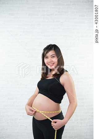 Pregnant woman measures belly circumference Pregnant woman measures belly circumference 43001807