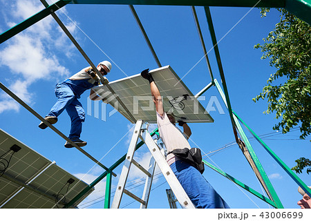 Workers command installing solar panels on the roof. 43006699