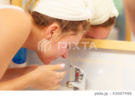 Woman washing face in bathroom. Hygiene Woman washing face in bathroom. Hygiene 43007499