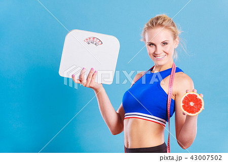 Fit woman holds weight scale grapefruit 43007502
