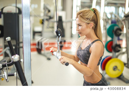 young blond woman doing exercise for her back in the modern gym. 43008834