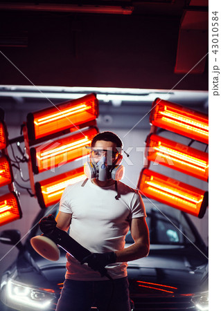 man wearing protective mask and glasses holding polishing machine 43010584