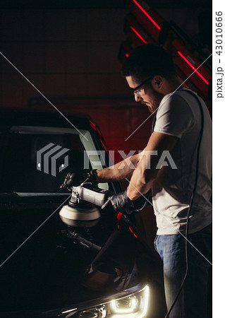 Car detailing - man with orbital polisher in auto repair shop. Selective focus. Car detailing - man with orbital polisher in auto repair shop. Selective focus. 43010666