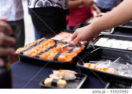 Hand picking sushi roll from food stall Hand picking sushi roll from food stall 43020982