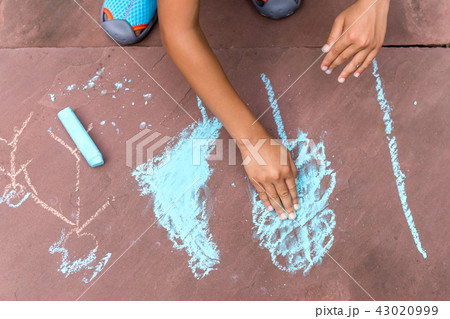 Boy drawing with coloured chalk on brick floor 43020999