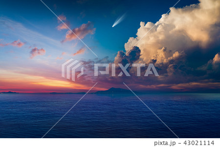 Bright comet in glowing sunset sky above dark sea 43021114