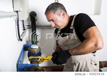 Plumber repairing metallic water pipes with wrench 43023410
