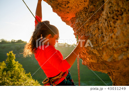 Photo of curly-haired female tourist clambering over rock Photo of curly-haired female tourist clambering over rock 43031249