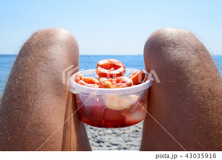 Peaches on the knees. Peeled peaches in a cup on male hairy legs. Beach vacation by the sea Peaches on the knees. Peeled peaches in a cup on male hairy legs. Beach vacation by the sea 43035916