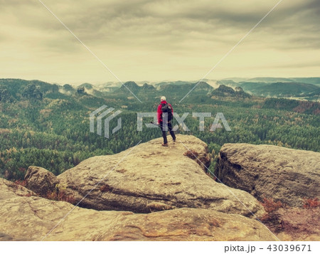 Alone hiker in warm red jacket stand on peak Alone hiker in warm red jacket stand on peak 43039671