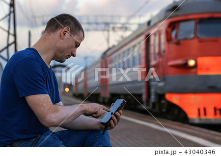 A man with a smartphone at the train station 43040346