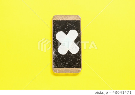 Mobile Smart Phone with cracked screen fixed with plaster on yellow 43041471