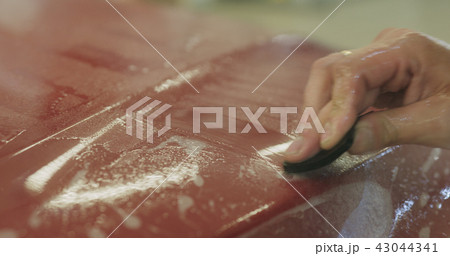 professional applying protective film to the red car 43044341