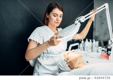 Beautician watches on patient face in mask Beautician watches on patient face in mask 43044720
