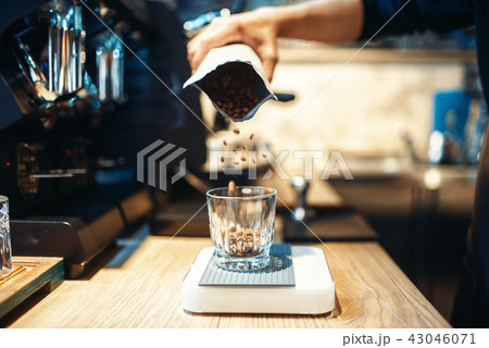Barista hand pours coffee beans into the glass 43046071