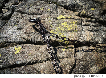 a rusty iron chain on a granite rock a rusty iron chain on a granite rock 43056064
