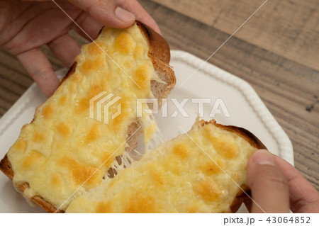 チーズたっぷりのトーストをちぎる 43064852