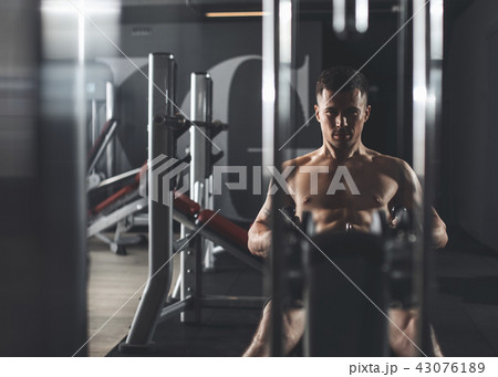 Concentrated man is exercising with machine in sport club Concentrated man is exercising with machine in sport club 43076189