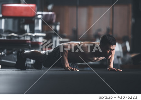 Motivated topless guy is doing push-ups indoor 43076223