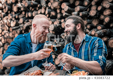Two smiling bearded men clanging their beer glasses 43083722