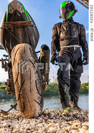 Man wearing motorcycle helmet and safety uniform sitting on bike outdoors, beautiful scenic 43085582