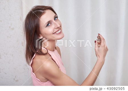 An attractive female spraying perfume on herself. An attractive female spraying perfume on herself. 43092505