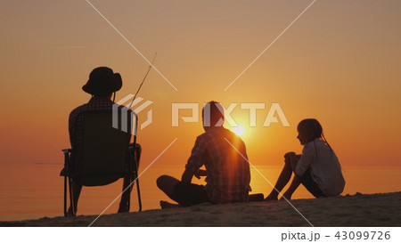 Three teenagers are fishing on the shore of the lake at sunset. Happy childhood concept 43099726