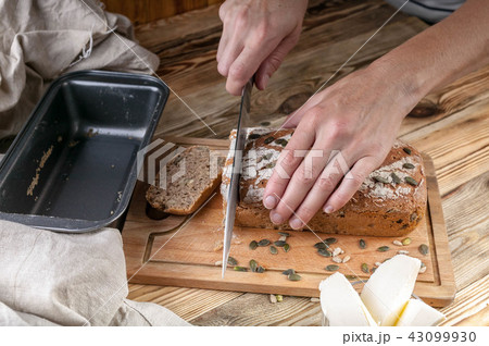 Female hands cut homemade bread on a wooden table Female hands cut homemade bread on a wooden table 43099930