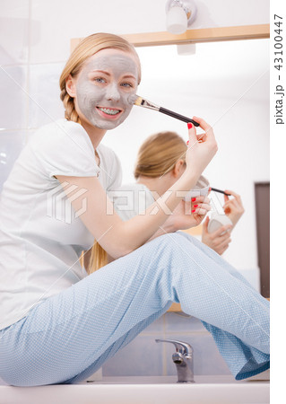 Woman applying with brush clay mud mask to her face Woman applying with brush clay mud mask to her face 43100447