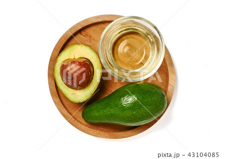 Top view of avocado oil and fresh avocado in wooden plate on whi Top view of avocado oil and fresh avocado in wooden plate on whi 43104085