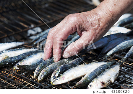 old woman salting some sardines in a grill 43106326