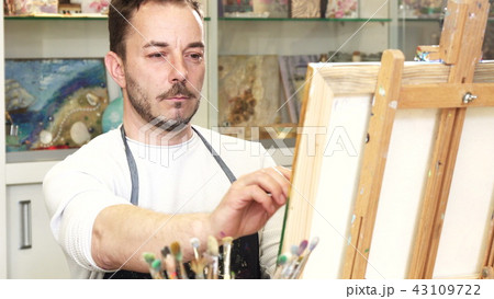 Mature male artist working on a painting at his art studio 43109722