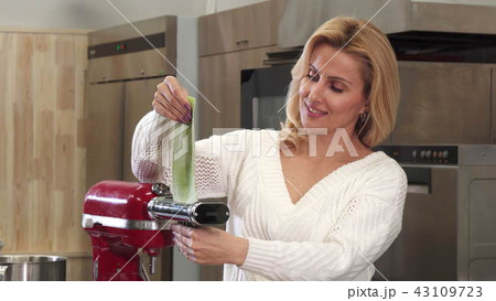 Beautiful mature housewife using pasta machine making homemade pasta 43109723