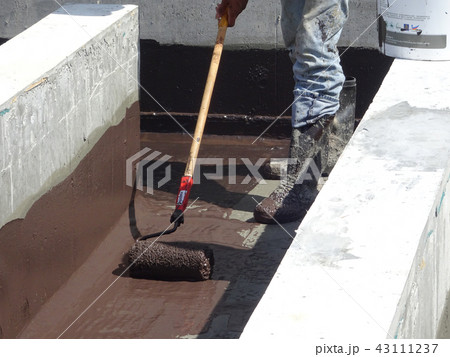 Waterproofing layer applied by construction worker Waterproofing layer applied by construction worker 43111237