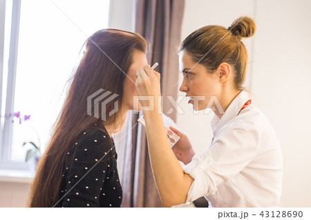 Make up artist doing professional make up of young woman 43128690
