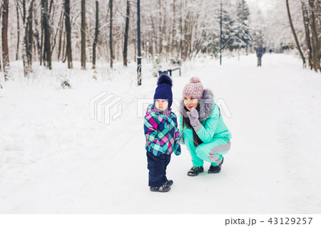 Winter, parents and children concept - mother and daughter walking and having fun on a snowy street 43129257