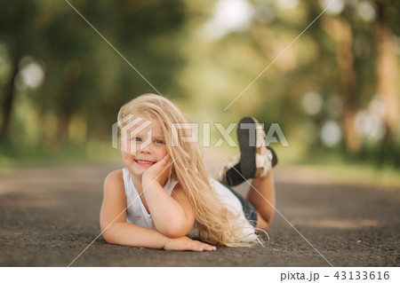 Little girl lie on the road near big alley 43133616