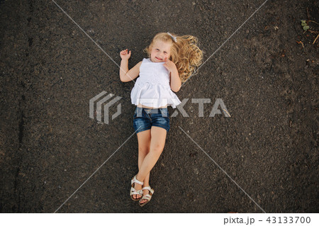 Little girl lie on the road near big alley 43133700