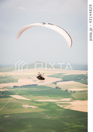 White orange paraglide with a paraglider in a cocoon against the background of fields of the sky and White orange paraglide with a paraglider in a cocoon against the background of fields of the sky and 43144829