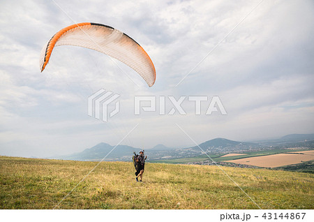 The paraglider opens his parachute before taking off from the mountain in the North Caucasus The paraglider opens his parachute before taking off from the mountain in the North Caucasus 43144867