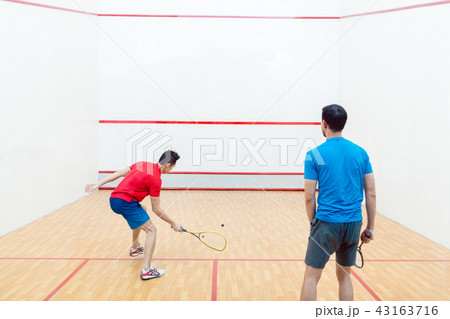 Rear view of two competitive young men playing squash game Rear view of two competitive young men playing squash game 43163716