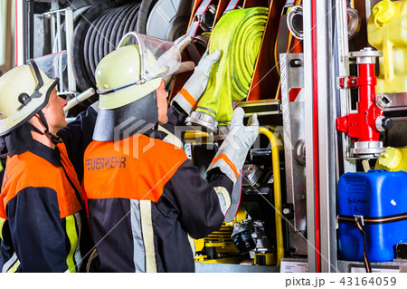 Fire fighters loading hoses into operations vehicle 43164059