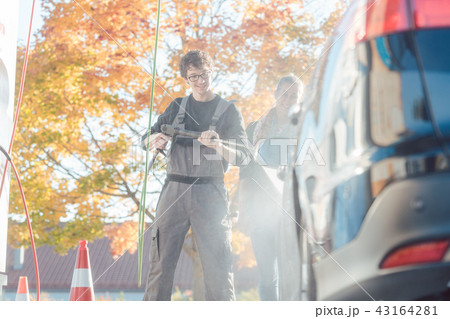Service man helping woman cleaning her auto in car wash 43164281