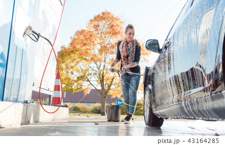 Woman cleaning her vehicle in self-service car wash 43164285